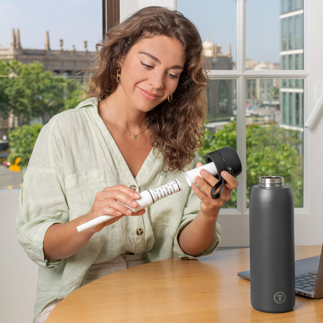 A black stainless steel water bottle with a flip-top lid on a light blue background.